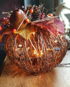 grapevine pumplin lit with mini lights and decorated on the top with fall follage and harvest minitures